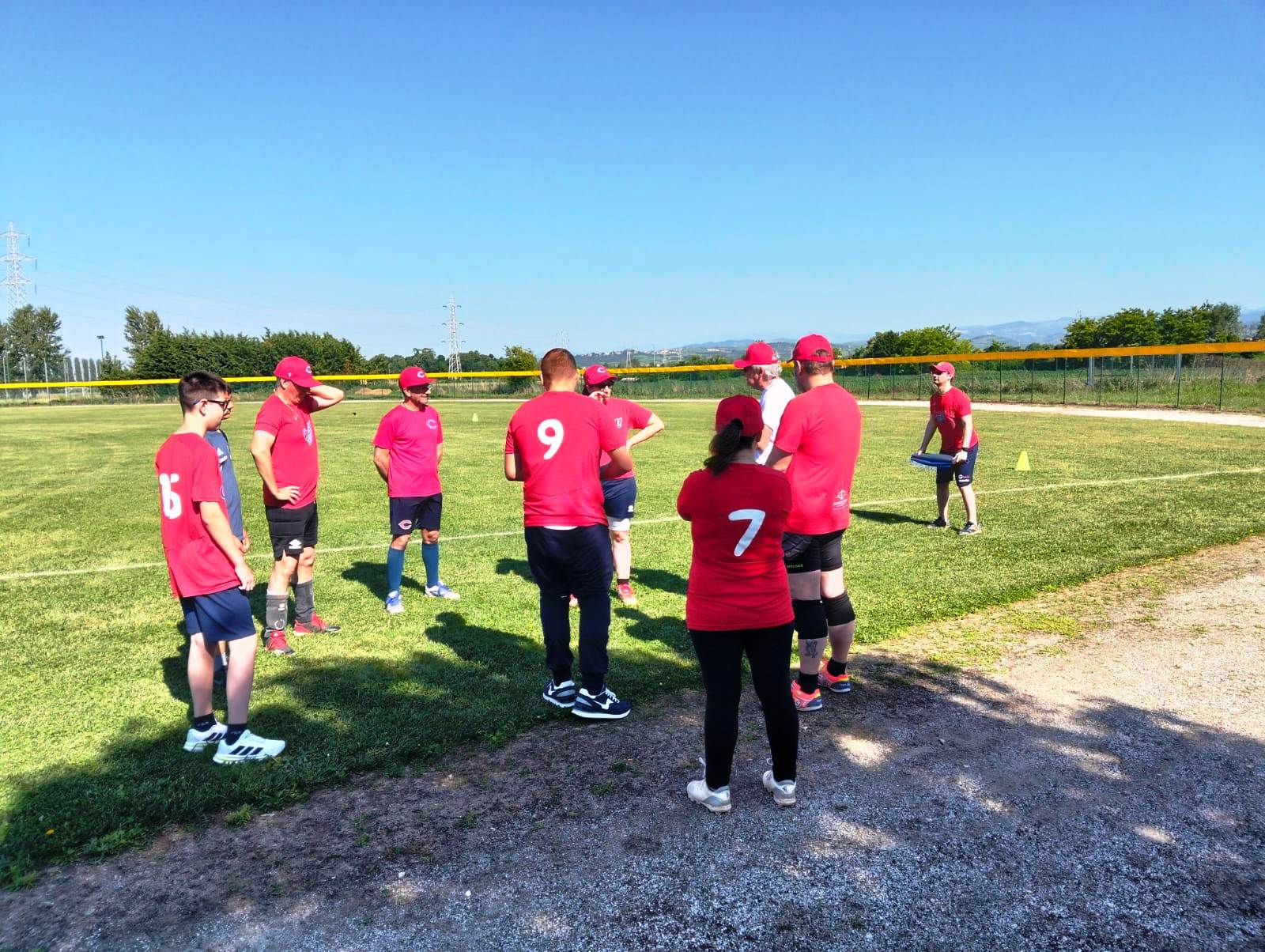 Un atleta si allena al baseball per ciechi affiancato da un assistente sul campo.